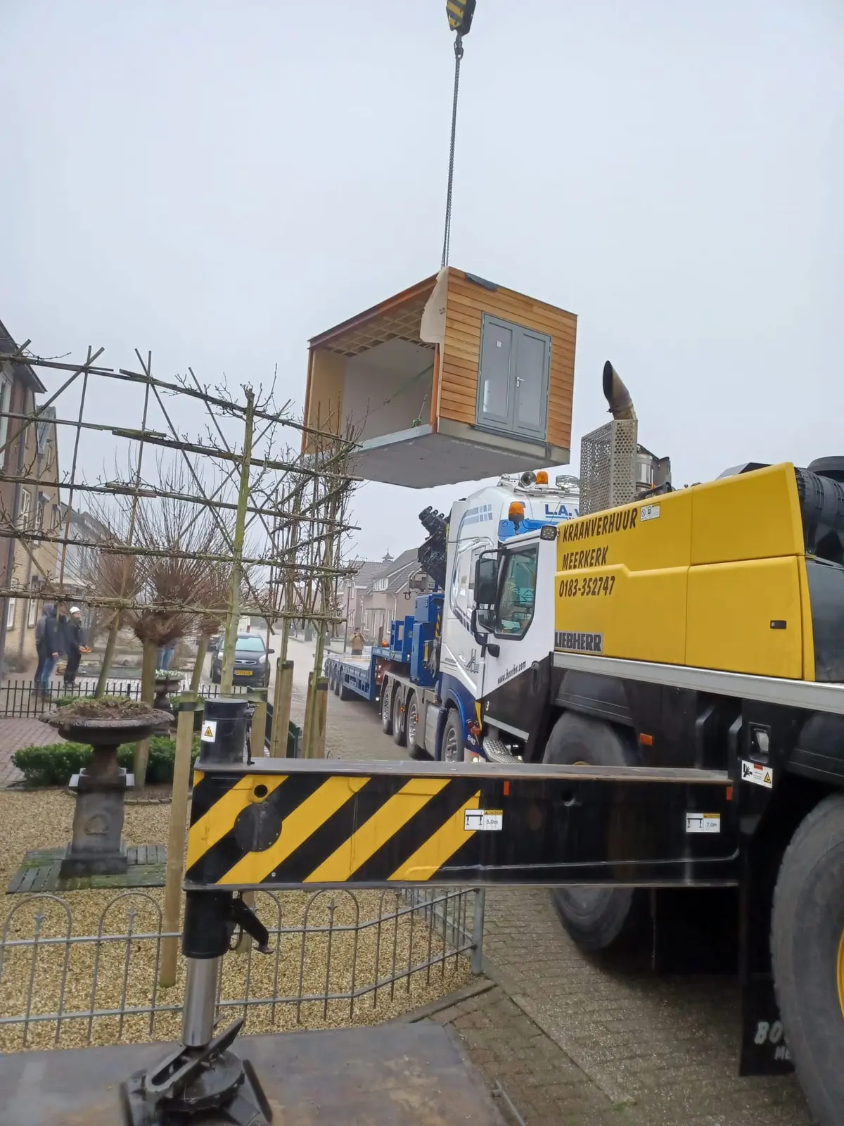 Prefab aanbouw wordt met een mobiele kraan over de woning getild