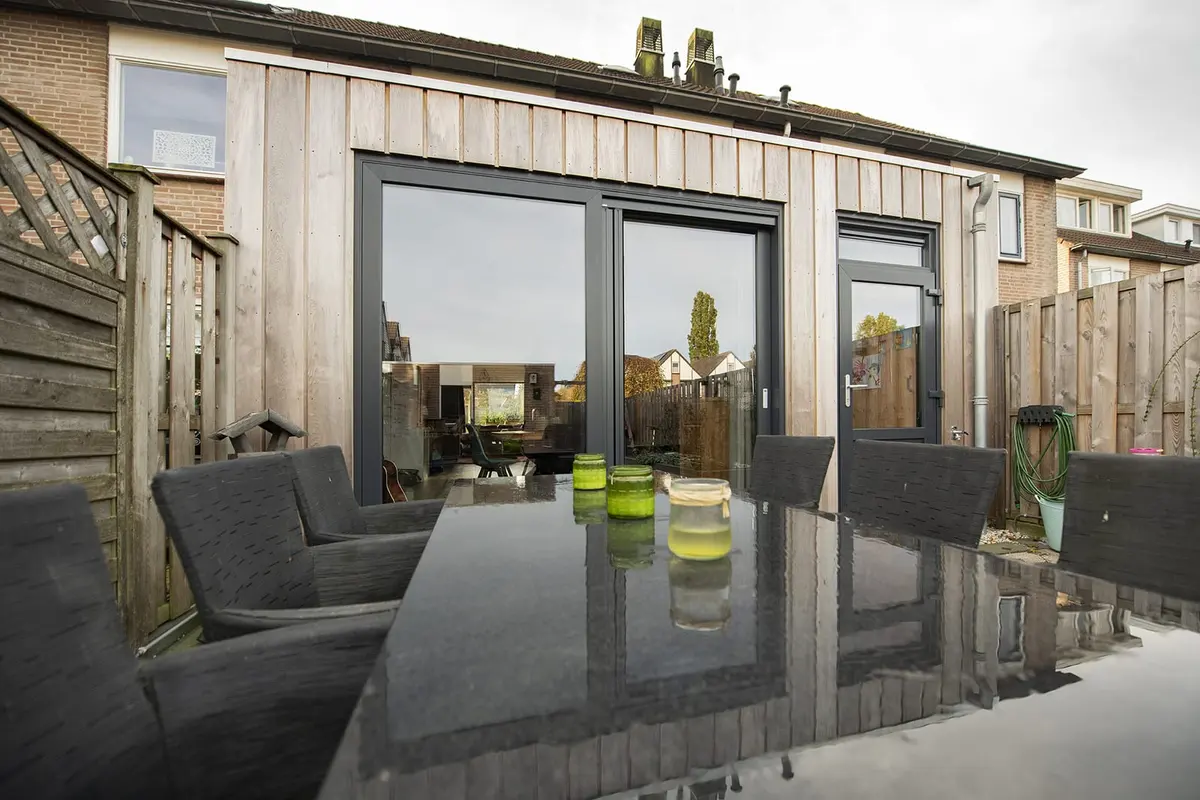 Tuintafel op het terras voor de aanbouw in Sleeuwijk met glazen pui en houten gevel