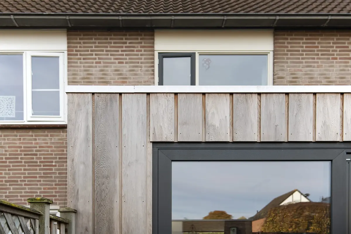 Aansluiting van de verticale houten gevelbekleding op het metselwerk van de bestaande woning