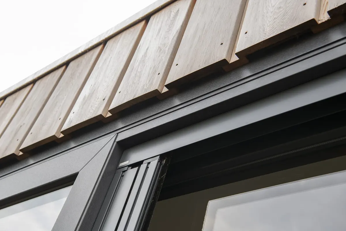 Antraciet kozijn onder de verticale houten gevelbekleding