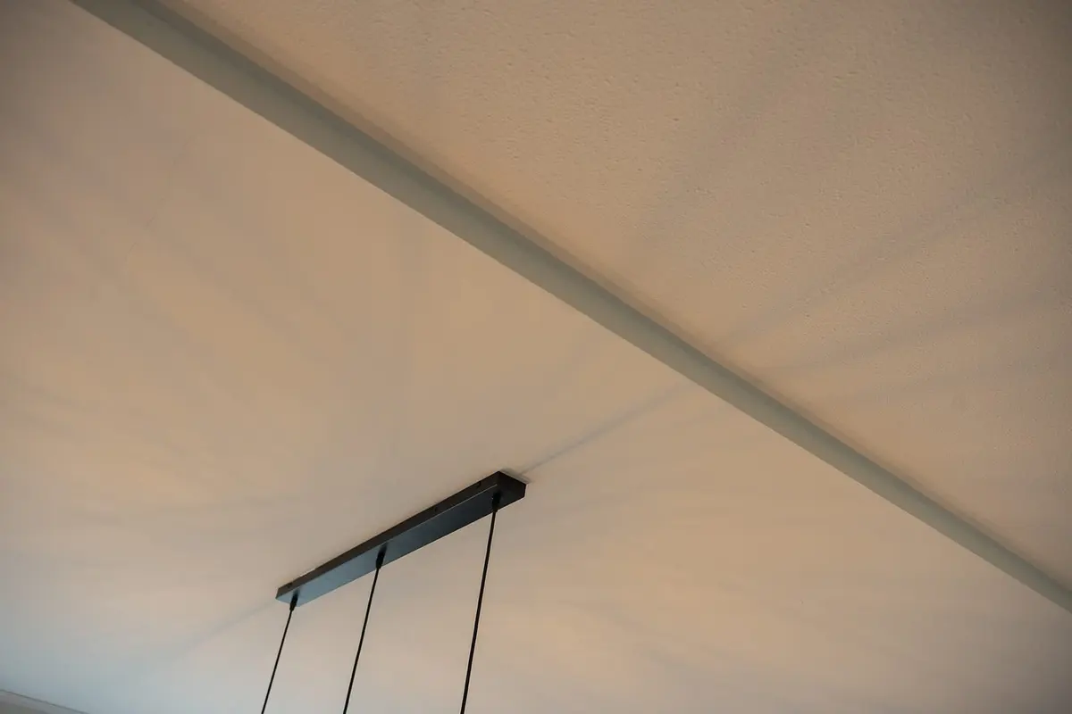 Strak afgewerkt plafond van de aanbouw met hanglamp