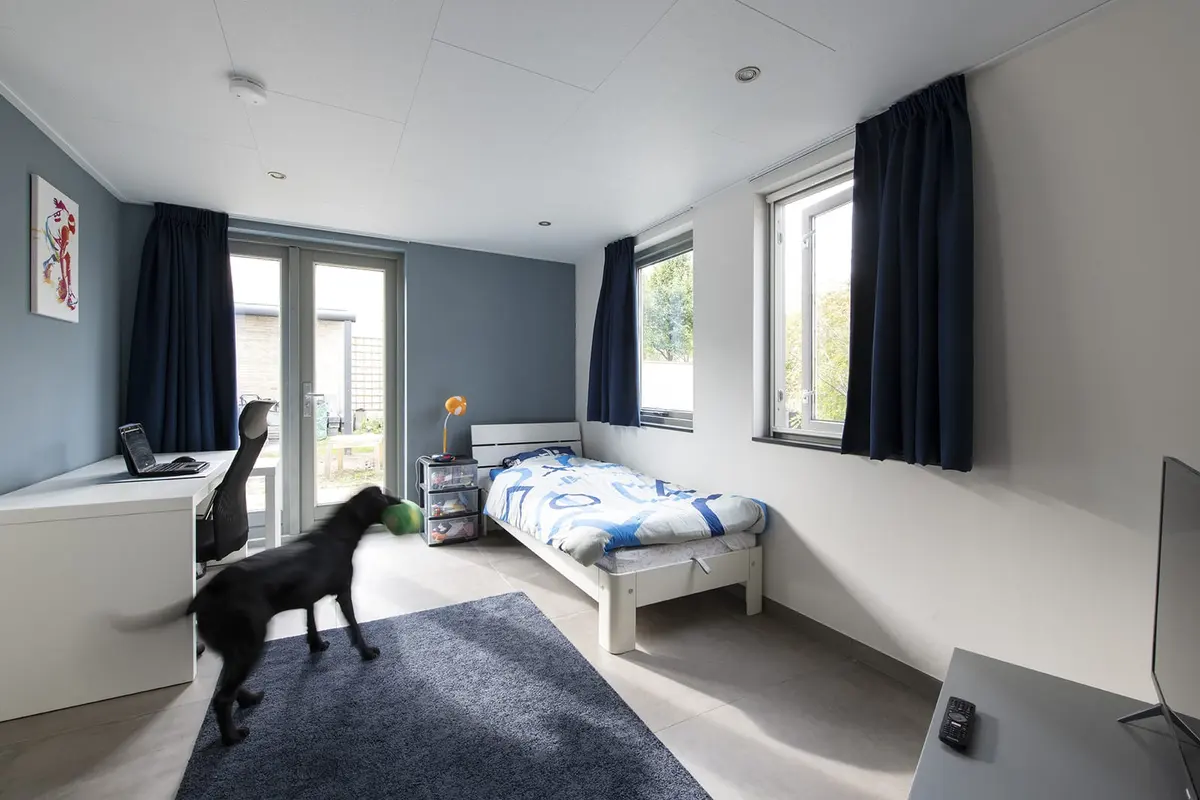 Lichte slaapkamer in de zorgaanbouw met grote ramen