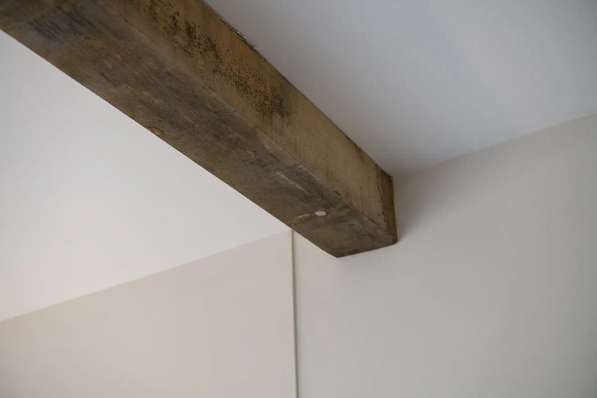 Houten balk op de overgang van de woning naar de aanbouw