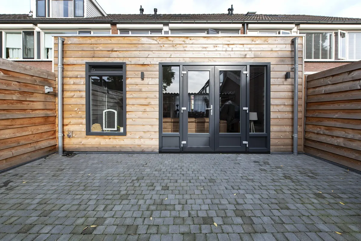 Prefab aanbouw in Wijk en Aalburg met liggende cederhouten gevelbekleding en openslaande deuren