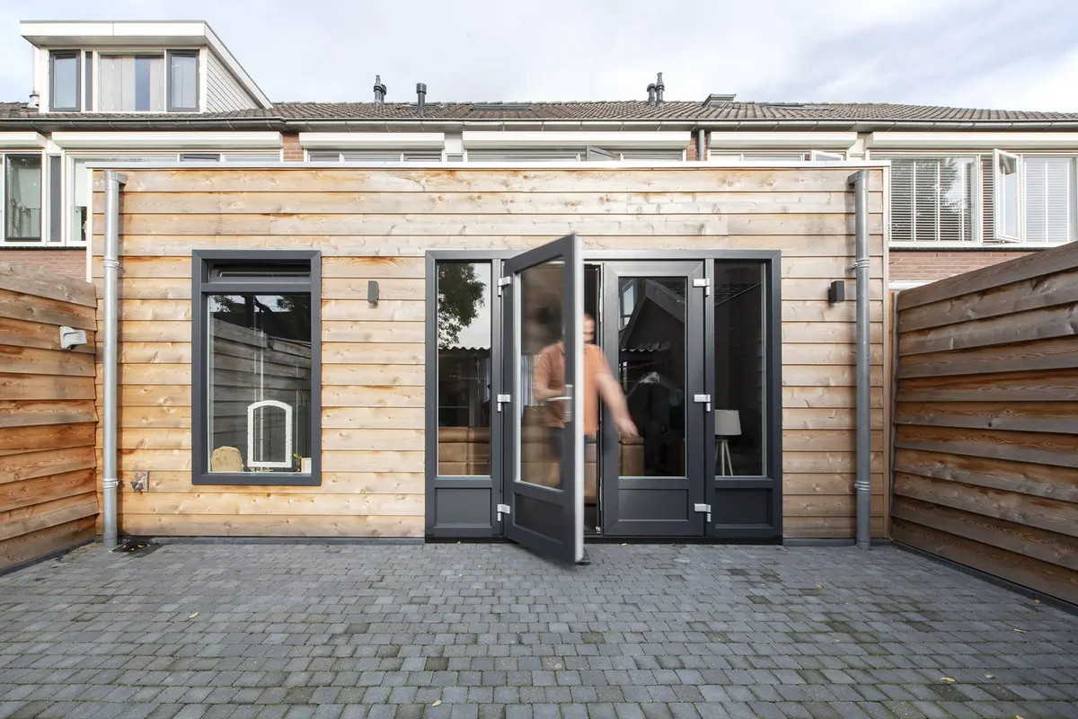 Bewoner opent de openslaande deuren van de aanbouw in Wijk en Aalburg