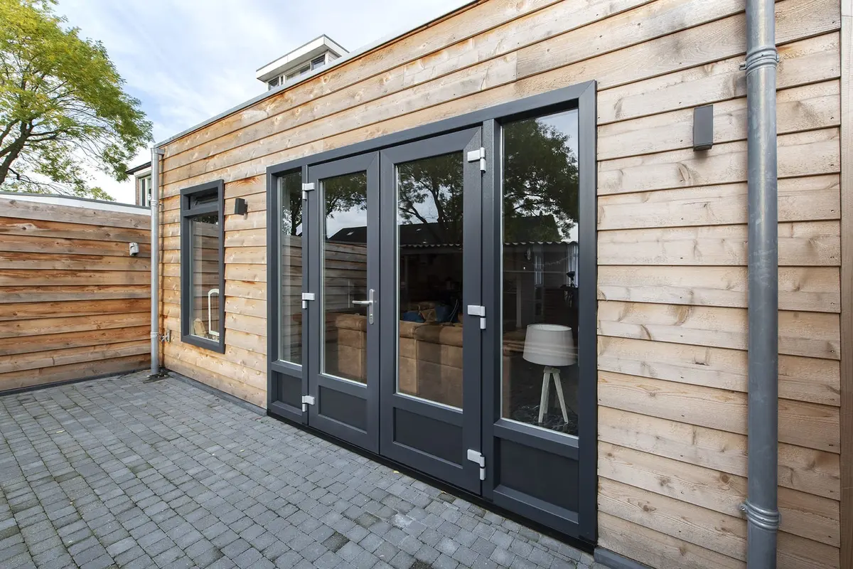 Antraciet openslaande deuren in de cederhouten gevel van de aanbouw